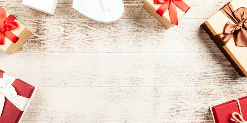 Mehrere eingepackte Geschenkboxen als Flatlay auf hellem Holz
