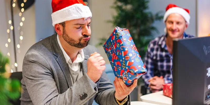 Mann betrachtet neugierig ein eingepacktes Geschenk